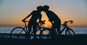 Two cyclists kissing during a sunset