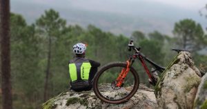 Best Mountain Bikes Under 1000: A man sitting on a rock looking at the beautiful view. His mountain bike is leaned against a rock.