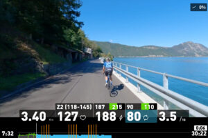 Wahoo SYSTM Review: Me riding "On Location" Italian lakes route in Wahoo SYSTM. The picture shows a road next to an Italian lake with a road cyclist in the middle.