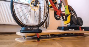 Why use a rocker plate: A rocker plate on a wooden floor with a bike trainer and a mounted bike (view from the floor level)