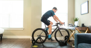 Indoor cycling guide for beginners: A man training on a Saris wheel-on bike trainer in his bedroom.