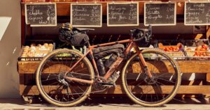 best gravel bikes under $5000: Canyon gravel bike with bags in front of a vegetable and fruit stand.