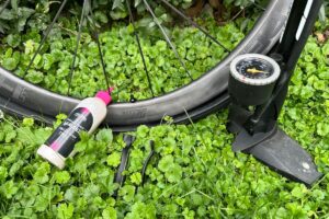 How to install tubeless tires? A tire sealant, tire levers, floor pump, and carbon wheels with tubeless tire in a grass.