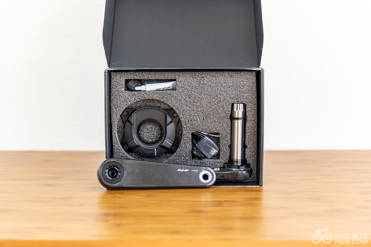Elilee X310 cranks and power meter in an opened box on a wooden table.