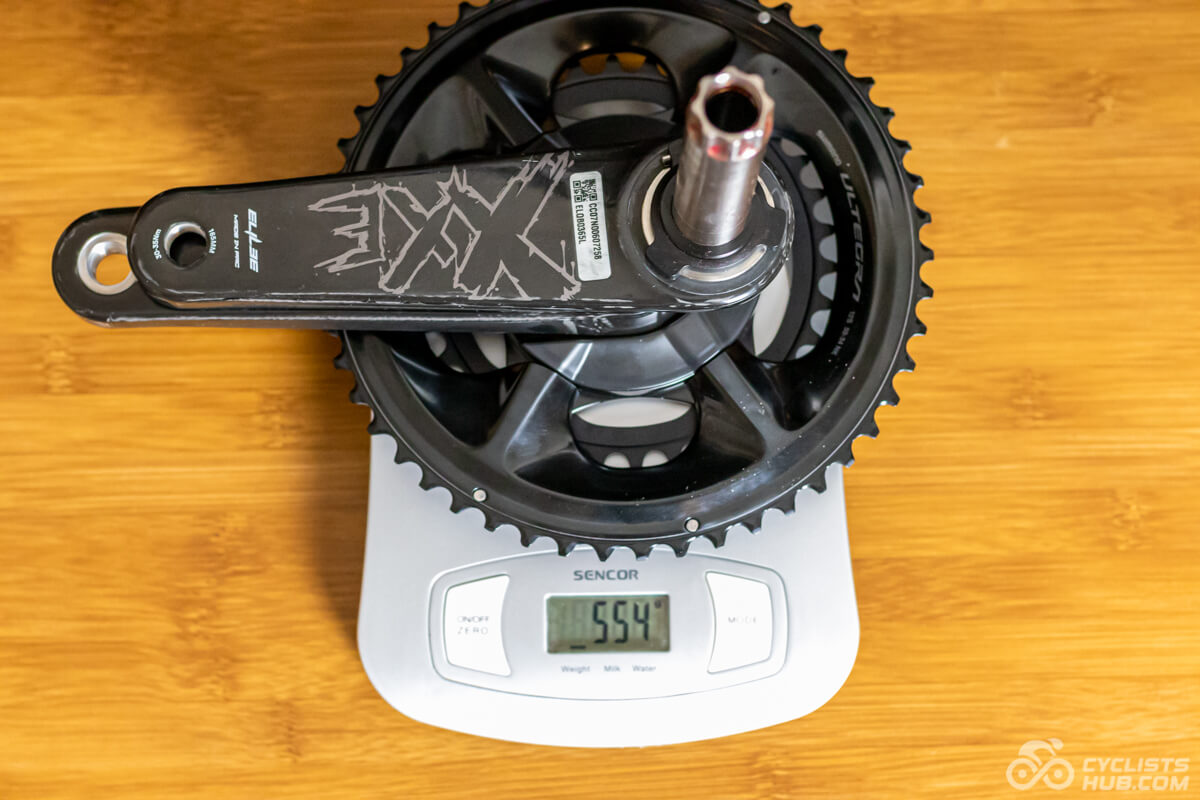 Elilee X310 cranks with the EK01 power meter and Shimano Ultegra 50x34T chainrings on a kitchen scale showing the weight of 554g.